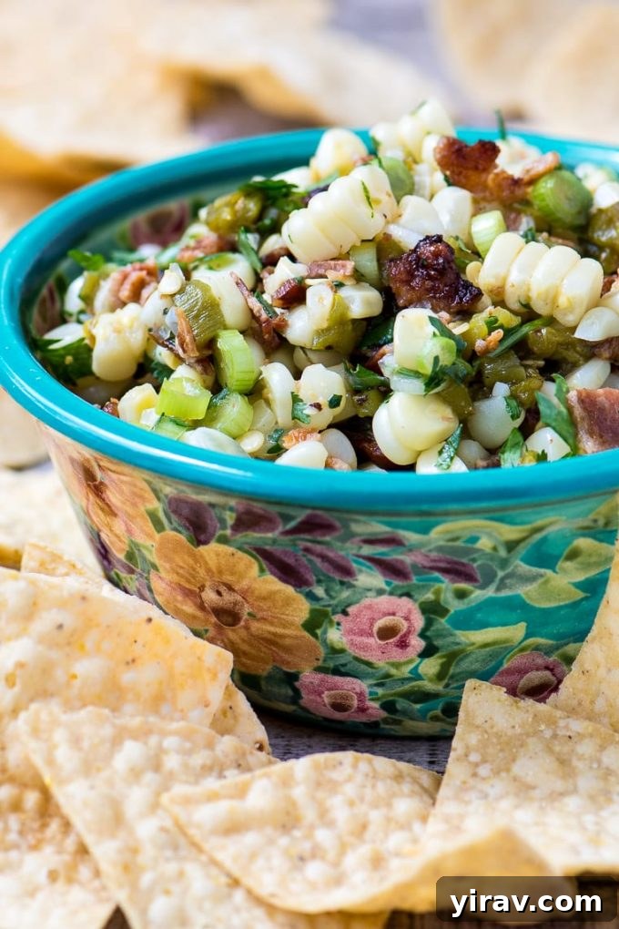 A beautiful floral bowl of Sweet Corn, Hatch Chile, and Bacon Salsa, surrounded by crisp tortilla chips.