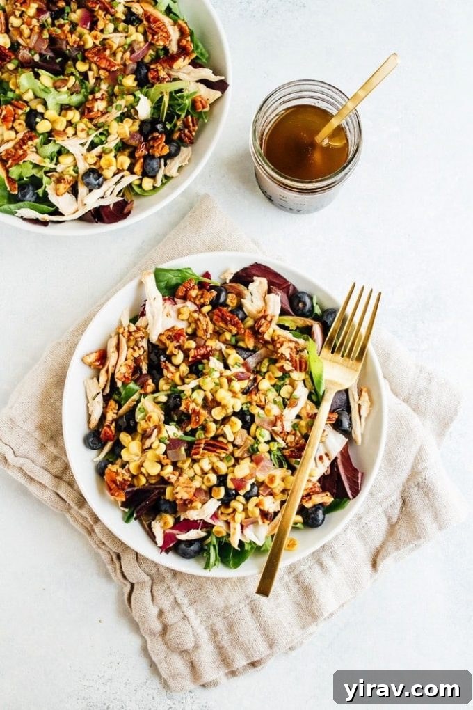 A bowl of refreshing Blueberry Corn Chicken Salad with a fork, garnished with fresh blueberries and cilantro.