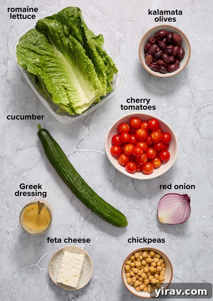 Vibrant Mediterranean Chop Salad 4 A spread of fresh Mediterranean salad ingredients including lettuce, tomatoes, cucumbers, red onion, feta, chickpeas, and olives.