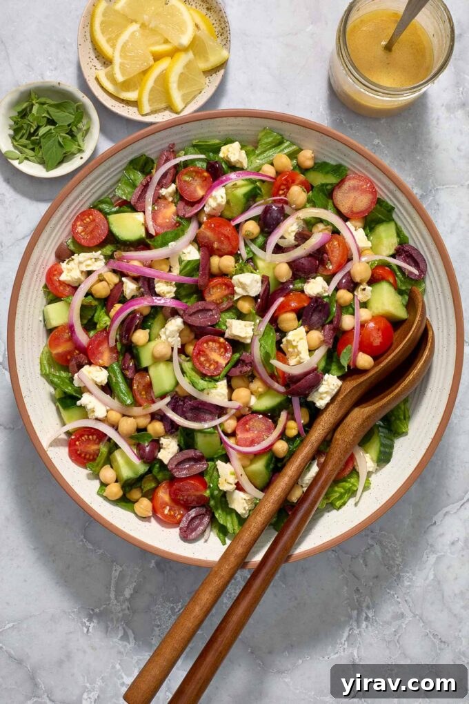 Vibrant Mediterranean Chop Salad 6 A vibrant Mediterranean Garbanzo Salad in a bowl, with serving utensils, ready to be enjoyed.