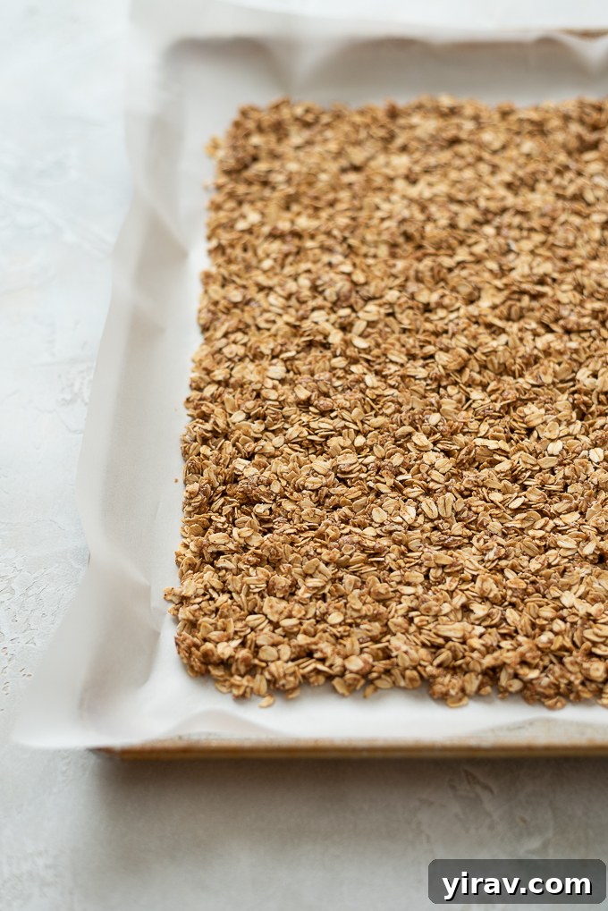 Step 3: Almond butter granola mixture packed down on a parchment-lined baking sheet.