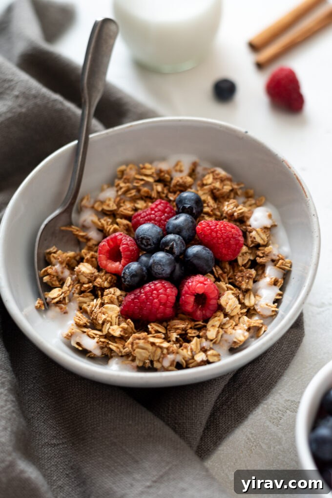 Almond butter granola in a bowl with milk and berries, ready to eat.
