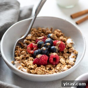 A bowl of homemade almond butter granola with berries and a drizzle of almond butter, ready to be enjoyed.