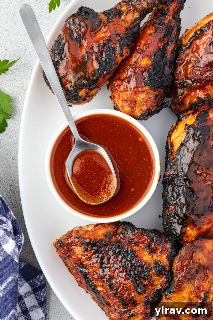 Crafted Bourbon BBQ Elixir 3 Bourbon bbq sauce in a bowl on a platter of bbq chicken