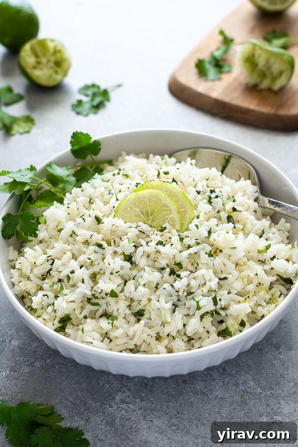 A close-up, front-facing shot of a white bowl filled with cilantro lime rice, with a cutting board and more fresh ingredients blurred in the background, highlighting the ready-to-eat dish.