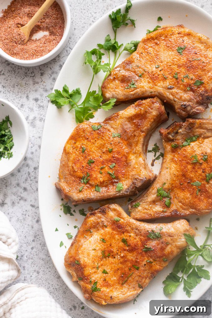 Tender Oven Baked Pork Chops 10 Easy baked pork chops on a platter with chopped parsley.
