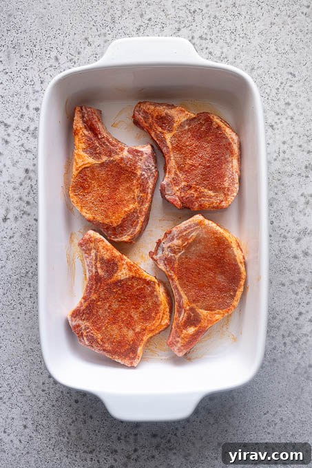 Tender Oven Baked Pork Chops 7 Seasoned pork chops in baking dish.