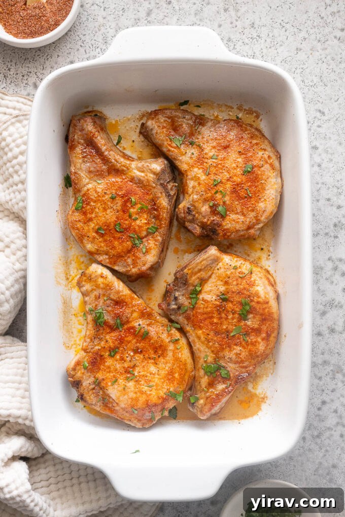 Tender Oven Baked Pork Chops 9 Juicy baked pork chops in baking dish with chopped parsley.