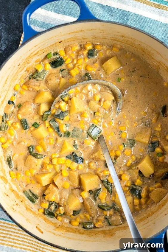 A rustic Dutch oven filled to the brim with creamy and comforting Poblano Corn Chowder.
