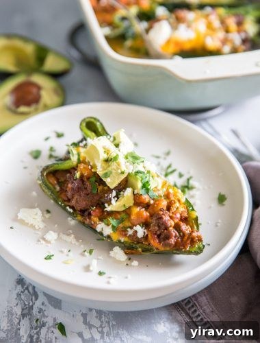 A perfectly cooked taco-stuffed poblano pepper elegantly presented on a stack of white plates.