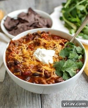 A large, inviting bowl of Beef Poblano Black Bean Chili, generously topped with sour cream, cheese, and cilantro.