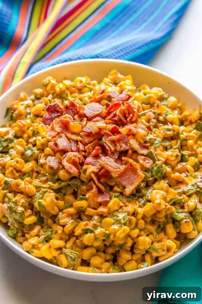 A large, vibrant bowl of Summer Corn Salad garnished with crumbled bacon, perfect for a picnic.
