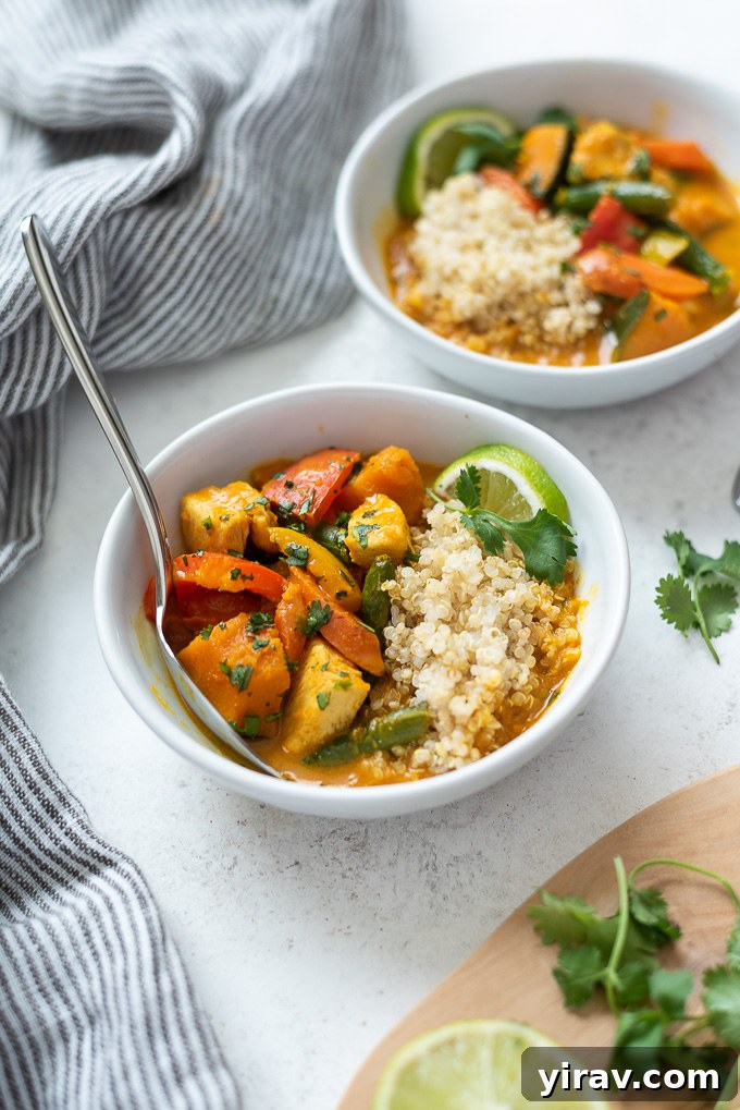 Creamy Thai Pumpkin Chicken Curry 8 A bowl of Thai pumpkin curry with quinoa, garnished with fresh cilantro and a lime wedge, ready to eat.