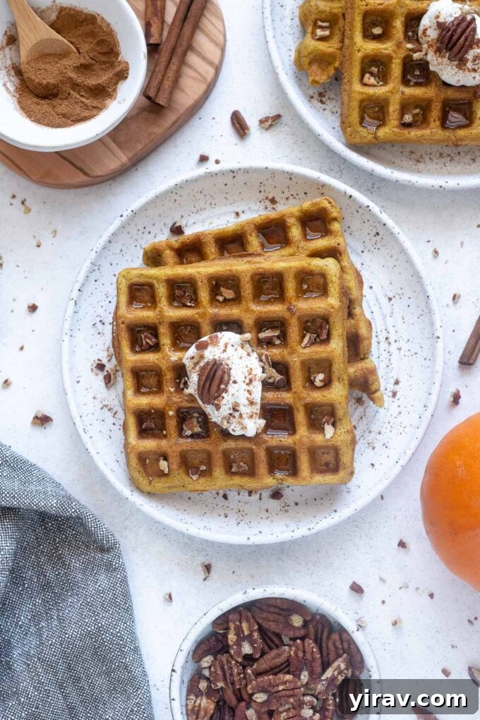 A stack of golden gluten-free pumpkin waffles on a white plate, ready to be served.