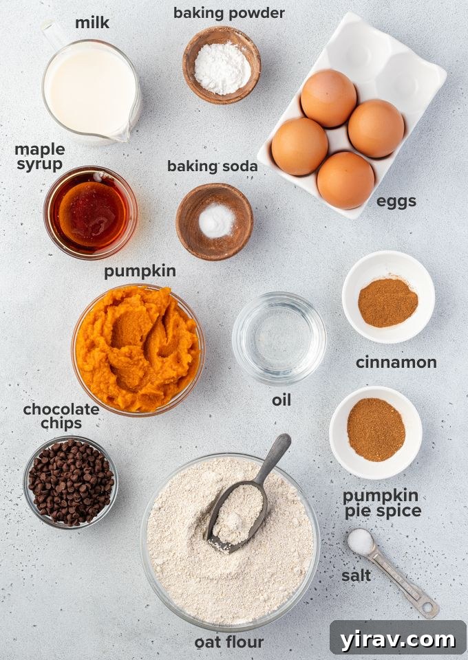 A flat lay photo showing all the essential ingredients for pumpkin oat flour waffles: oat flour, eggs, pumpkin puree, maple syrup, milk, coconut oil, baking powder, pumpkin pie spice, and salt.