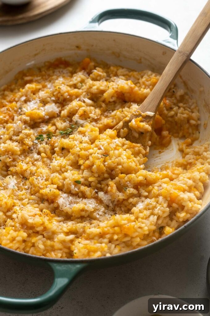 Velvety Pumpkin Risotto 6 Close-up of creamy pumpkin risotto in a skillet with a wooden spoon, ready to be served.