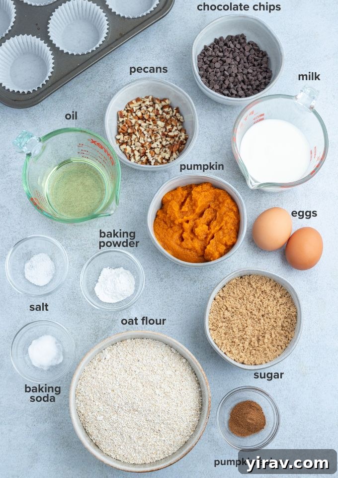Oatmeal pumpkin muffins recipe ingredients like flour, eggs, pumpkin puree, and spices laid out on a counter.