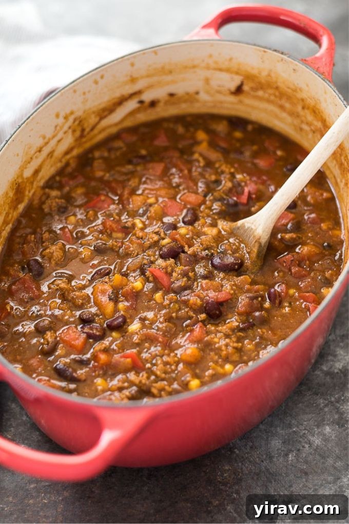 Turkey pumpkin chili simmering in a large orange Dutch oven, ready to be served, highlighting its thick texture and rich color.