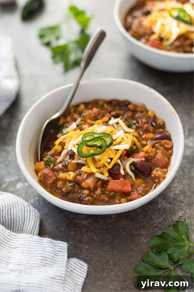 A close-up shot of turkey pumpkin chili in a bowl with a spoon, highlighting the thick, rich consistency and delicious ingredients.