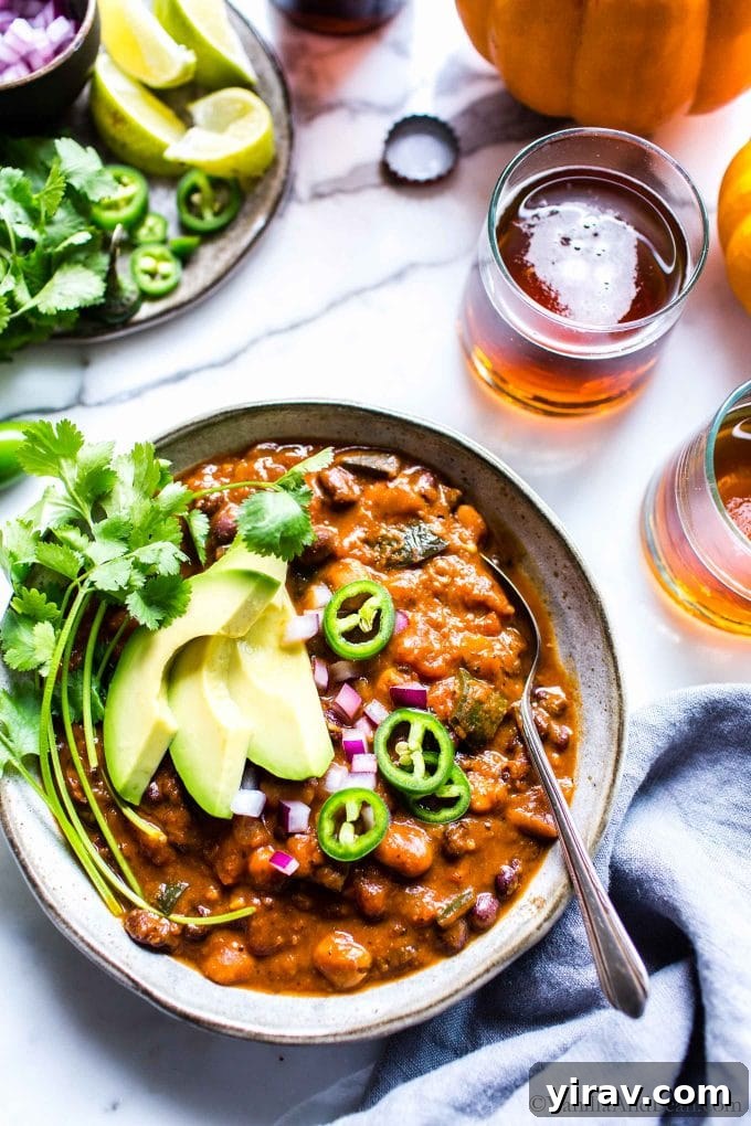 Overhead view of a bowl of kabocha squash chili topped with avocado, jalapeno slices, and cilantro.