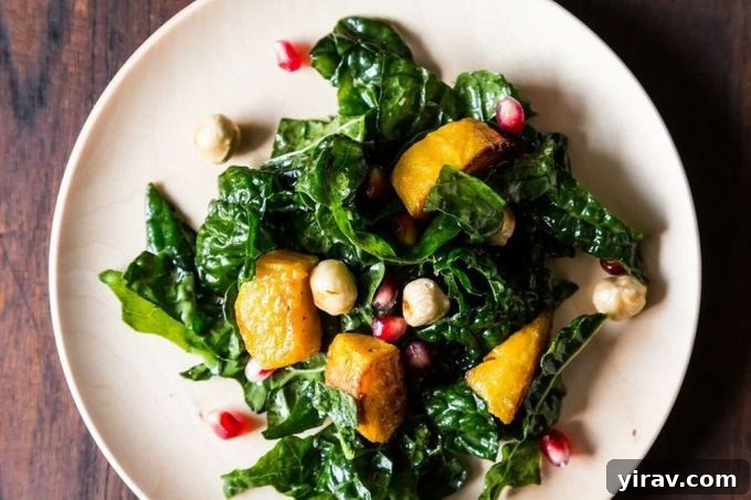 Overhead view of a kale salad with kabocha squash and pomegranate aerils.