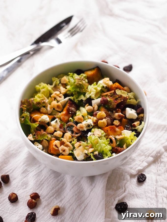 A bowl of kabocha squash salad. A knife and fork rest in the background.