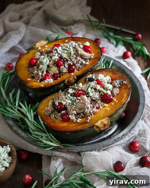 Two lamb-stuffed kabocha squash halves on a metal plate. Fresh rosemary and cranberries surround the plate.