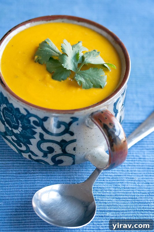 A mug full of Thai kabocha soup, with a spoon resting nearby.