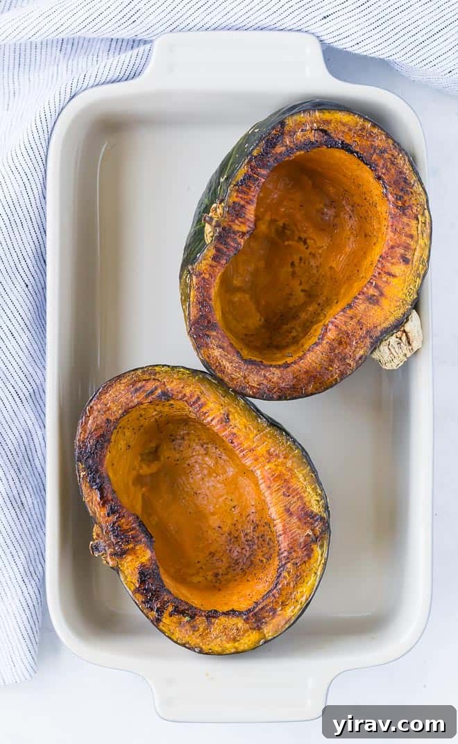 Overhead view of two roasted kabocha squash halves in a baking dish.