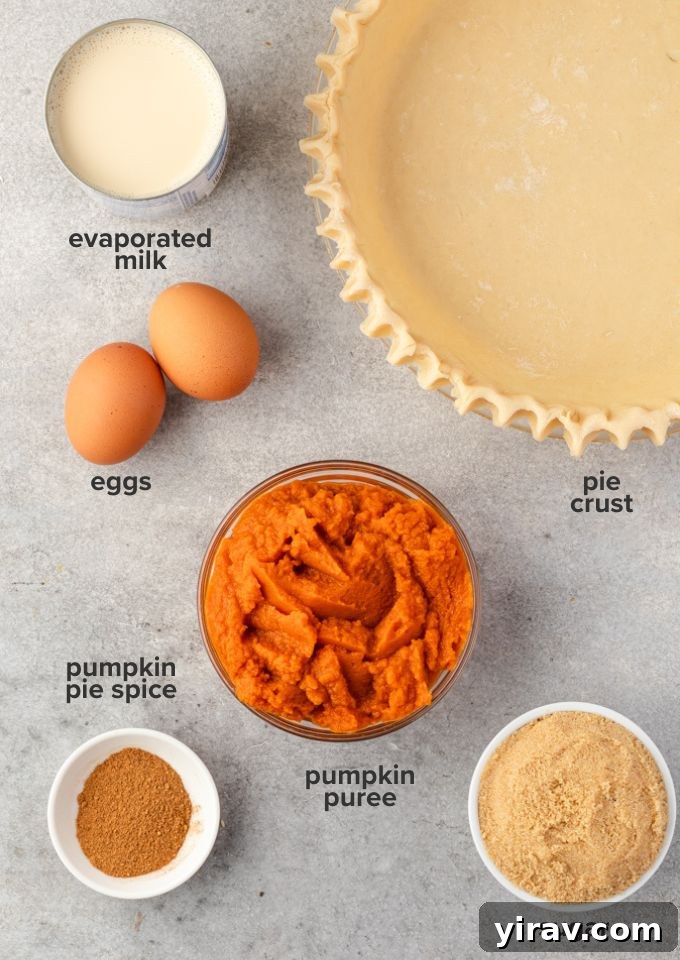 Perfect Homemade Pumpkin Pie 4 Various ingredients for homemade pumpkin pie laid out on a wooden surface, including pumpkin puree, eggs, milk, sugar, and spices