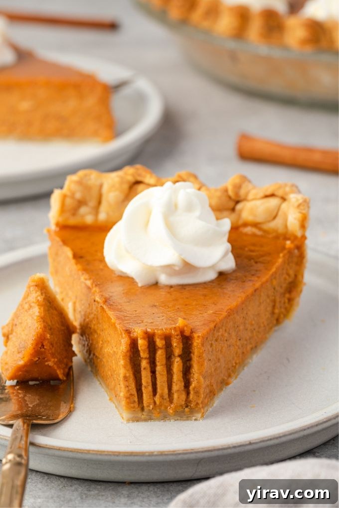 Perfect Homemade Pumpkin Pie 8 A slice of homemade pumpkin pie with a bite taken out, highlighting the creamy filling and flaky crust
