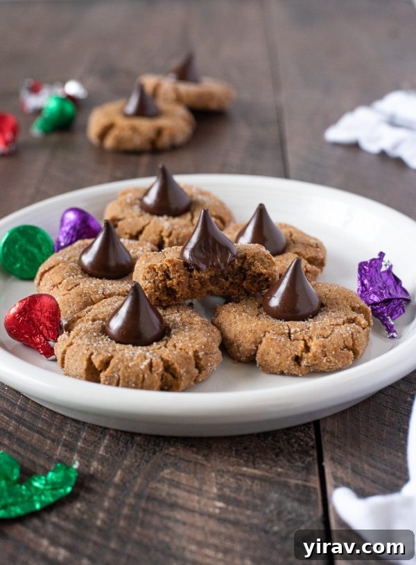Gluten-free peanut butter blossoms on a white plate with a bite taken out of the top cookie
