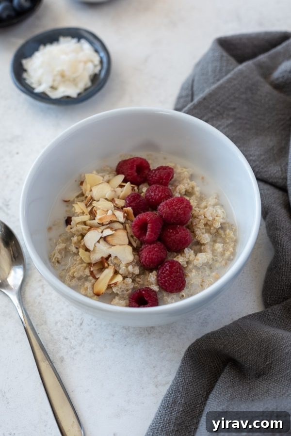 Close-up of a vanilla almond raspberry quinoa breakfast bowl, showcasing fresh raspberries and crunchy sliced almonds atop creamy oatmeal.
