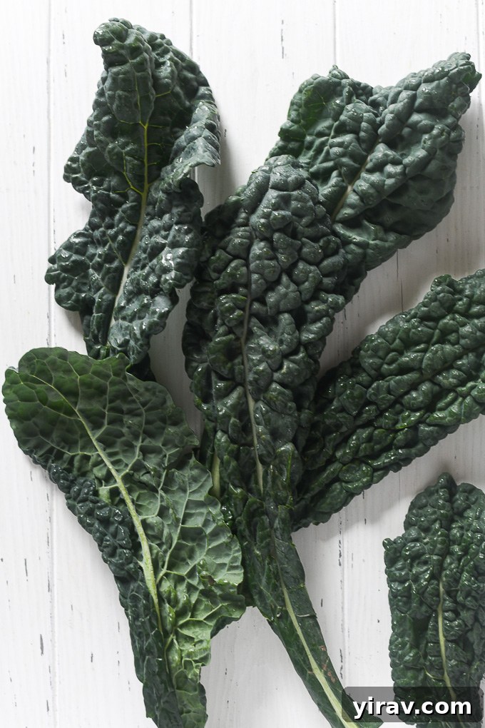 Silky Kale Salad 3 Fresh ingredients for a massaged kale salad including bunches of kale, a lemon, olive oil, and a block of parmesan cheese.