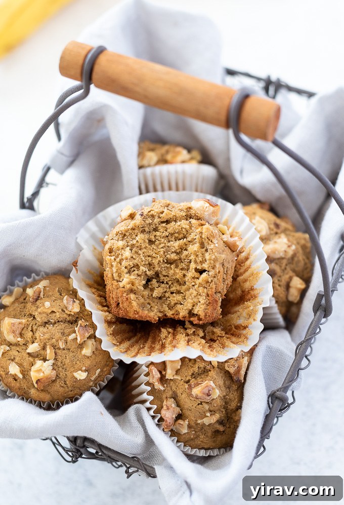A close-up shot of healthy banana oat muffins in a basket, with one muffin having a bite taken out, revealing its moist interior.