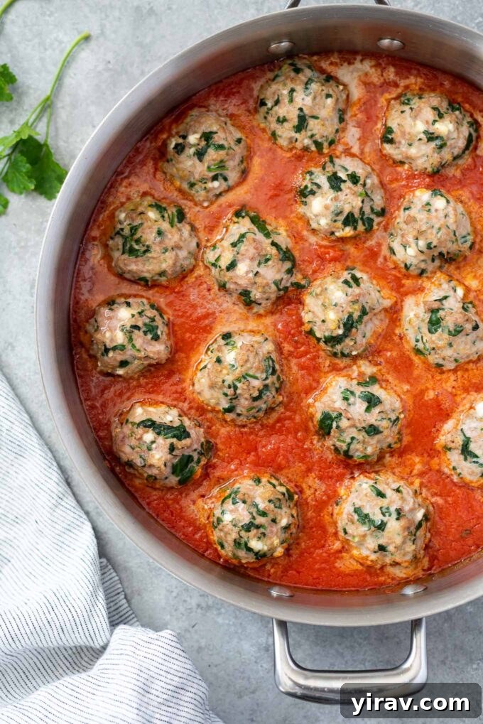 Oven Baked Turkey Meatballs in a skillet with rich marinara sauce, garnished with fresh herbs.