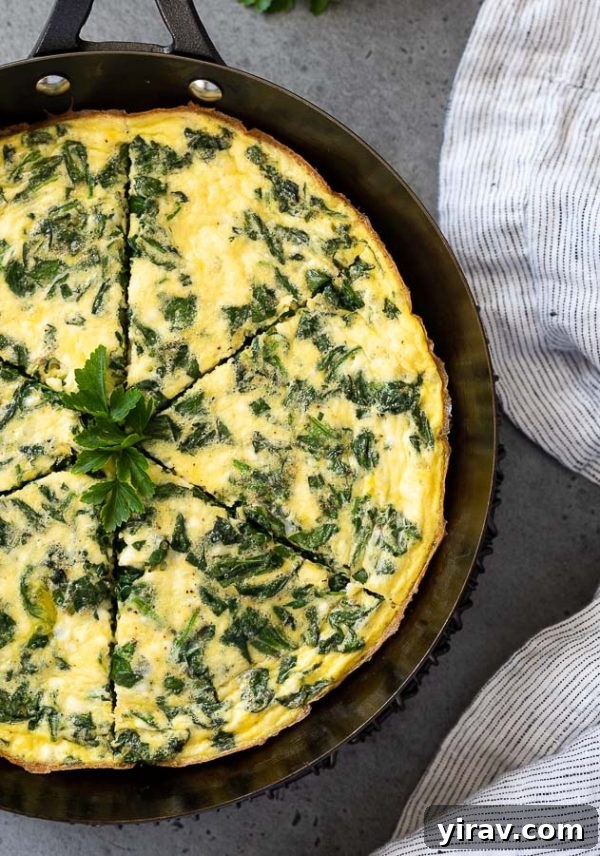 Close-up overhead shot of a perfectly cooked spinach and feta frittata, cut into neat slices in a cast iron skillet.