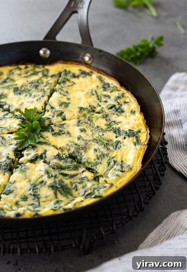 Sliced spinach frittata in skillet, highlighting the individual portions and the vibrant filling.