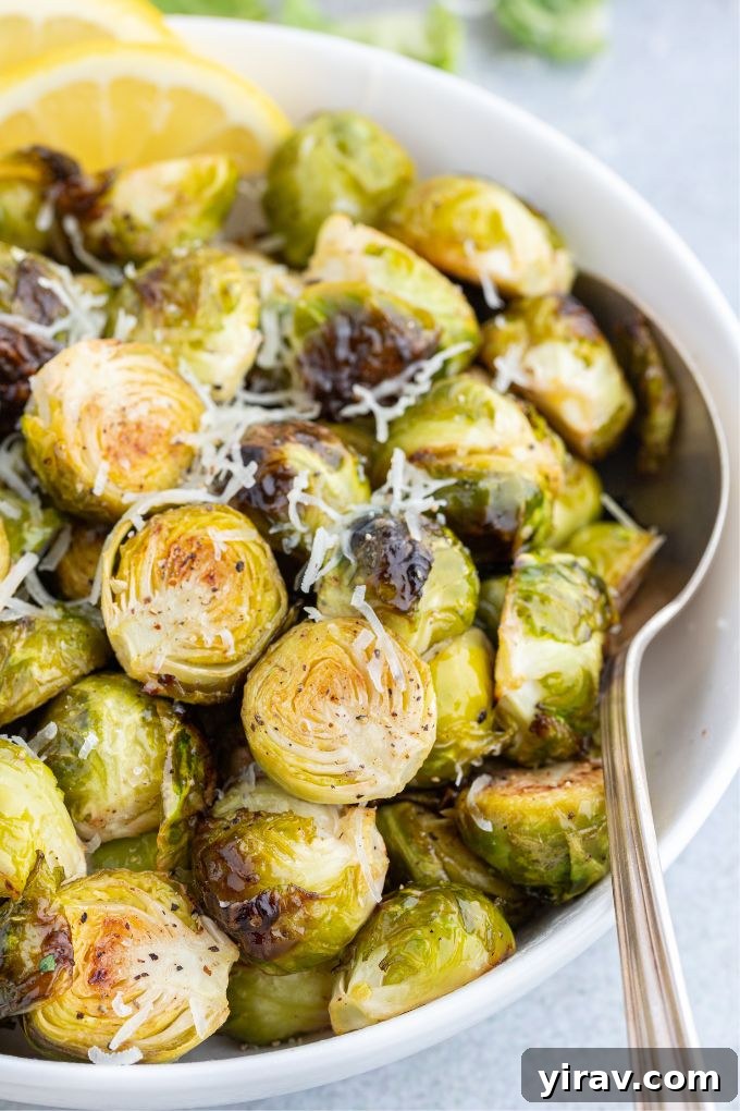 Crispy Air Fryer Brussels Sprouts 7 A simple white bowl filled with freshly air-fried Brussels sprouts and a serving spoon, highlighting their rustic charm.