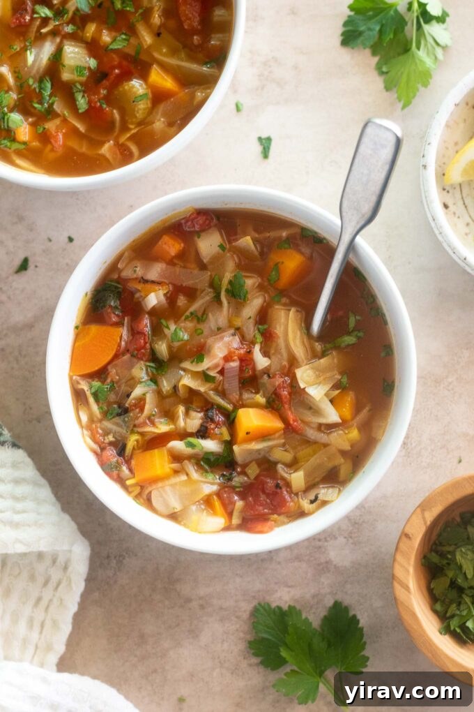 A comforting bowl of Cabbage Soup with a spoon, highlighting its nutritious and hearty ingredients.