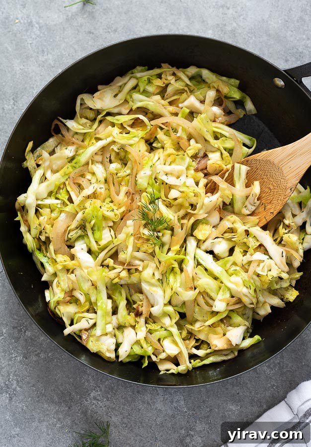 Simple sautéed cabbage and onions in a skillet with a wooden spoon, showcasing its caramelized goodness.