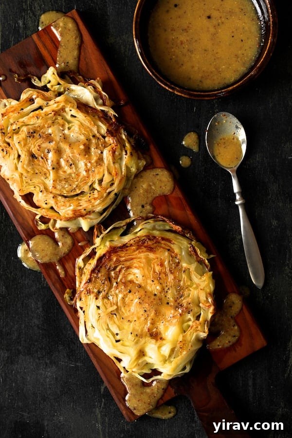 Overhead view of two perfectly roasted cabbage steaks, drizzled with mustard vinaigrette.