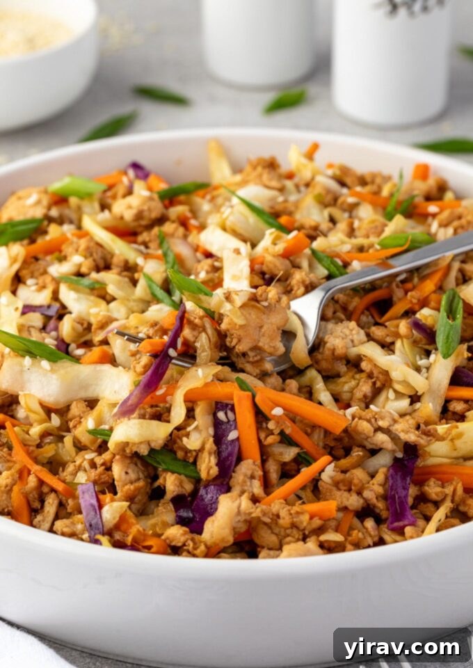 A fork digging into a flavorful Egg Roll in a Bowl, showcasing the healthy, low-carb ingredients.