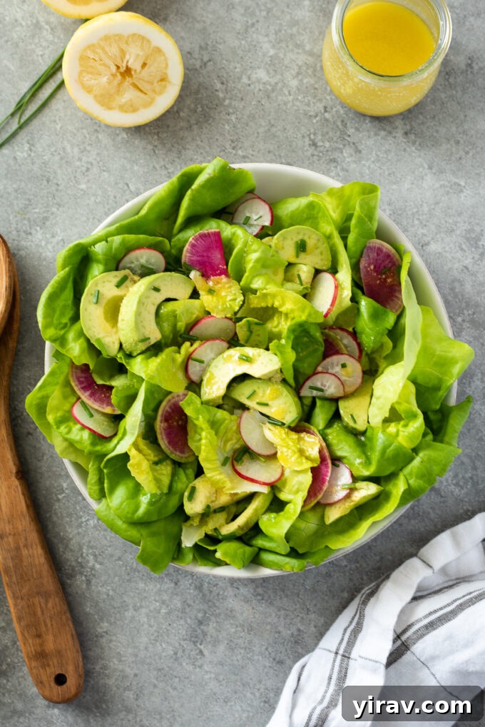 Close-up of butter lettuce salad in a rustic ceramic bowl, highlighting the creamy avocado and thinly sliced radishes.