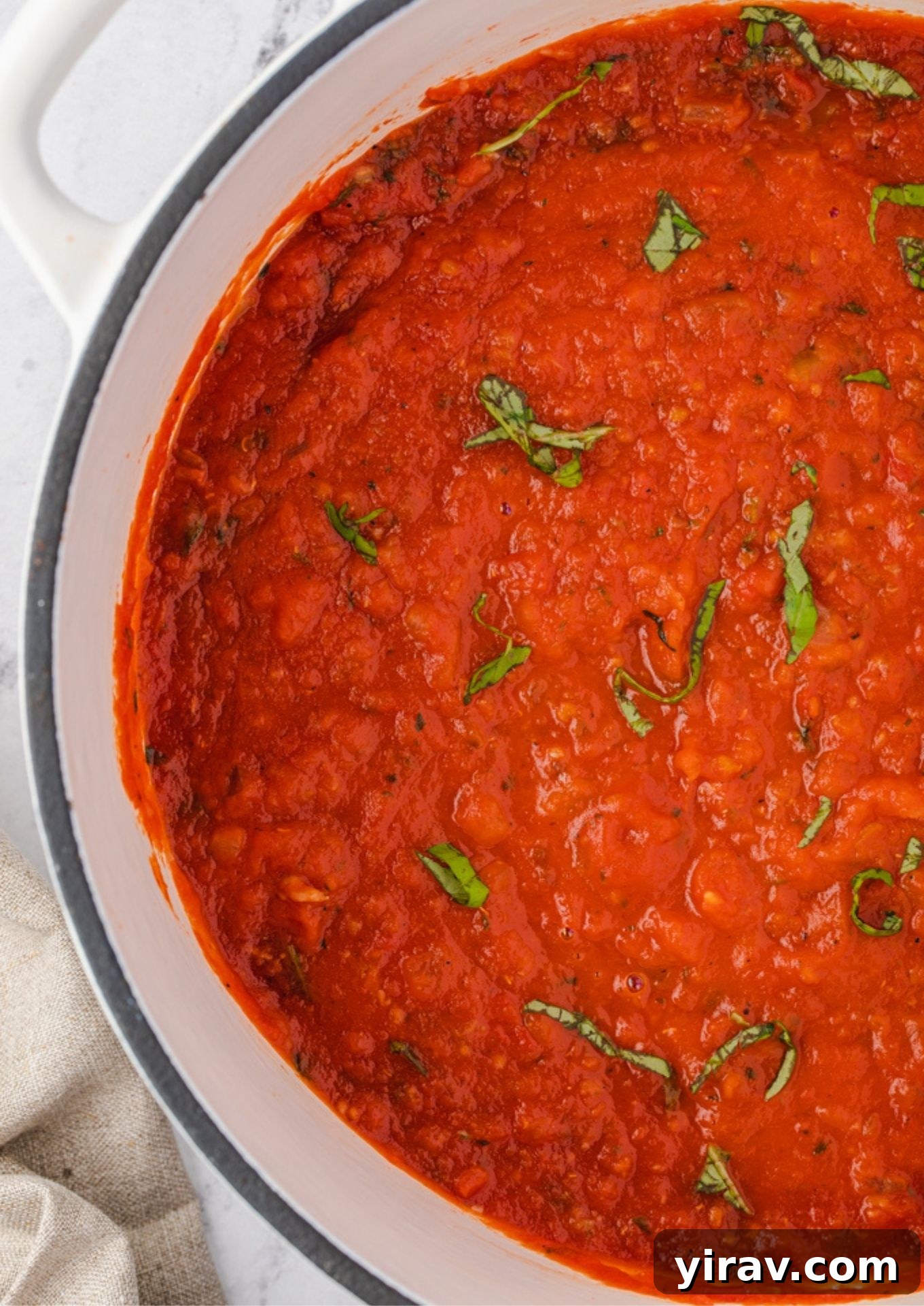 Homemade marinara sauce in a dutch oven with basil on top
