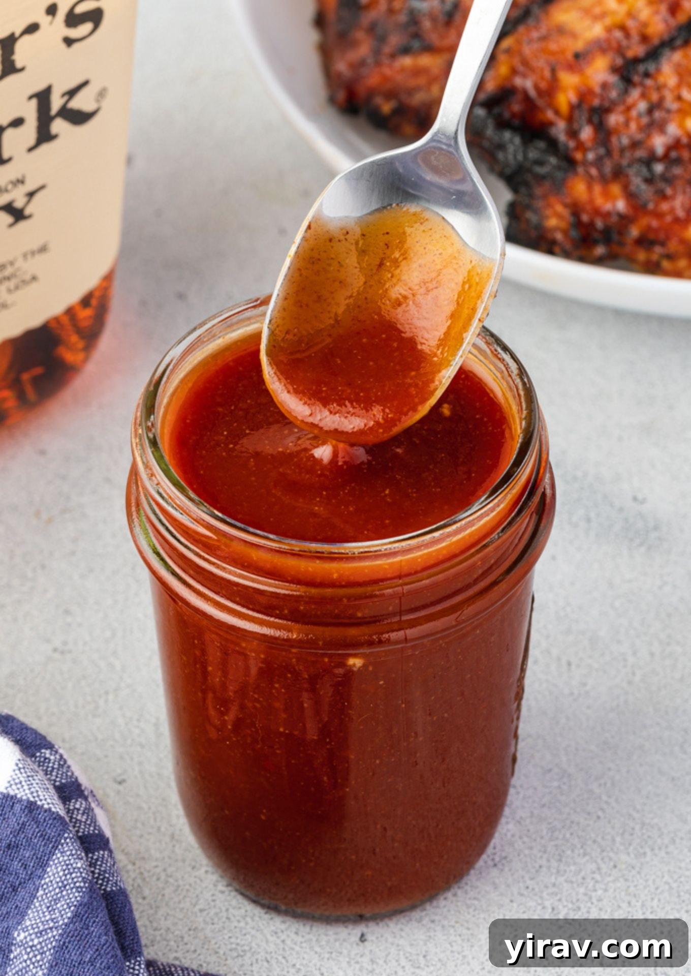 Spoon drizzling bourbon bbq sauce into a jar