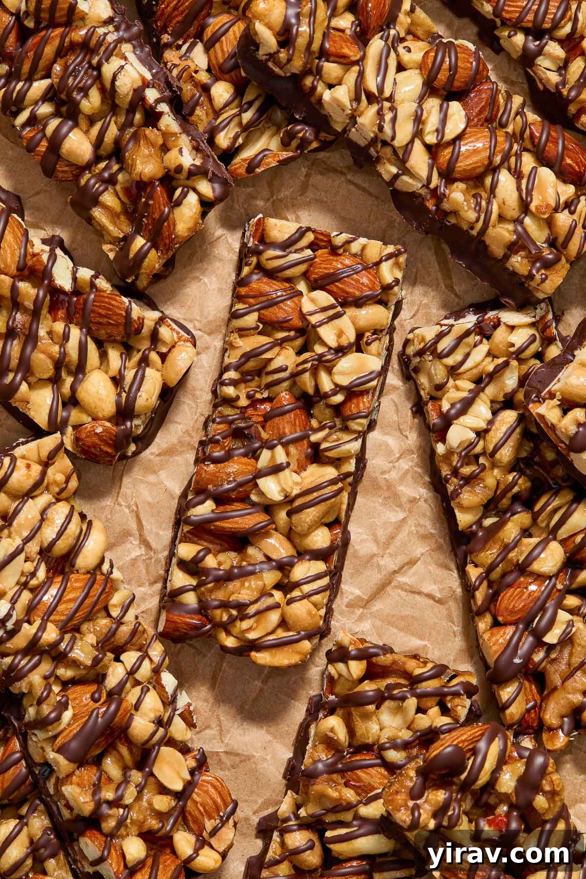 Nut bars covered in dark chocolate on parchment paper.