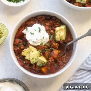 Butternut squash turkey chili in a bowl topped with avocado and sour cream.