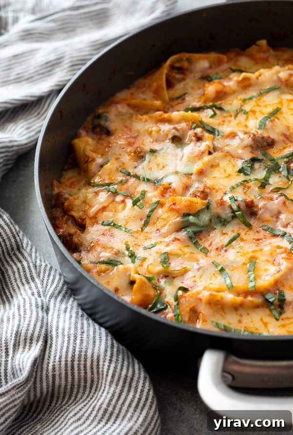 Close up of stove top lasagna with chopped basil on top and linen alongside, emphasizing its fresh ingredients and readiness for serving
