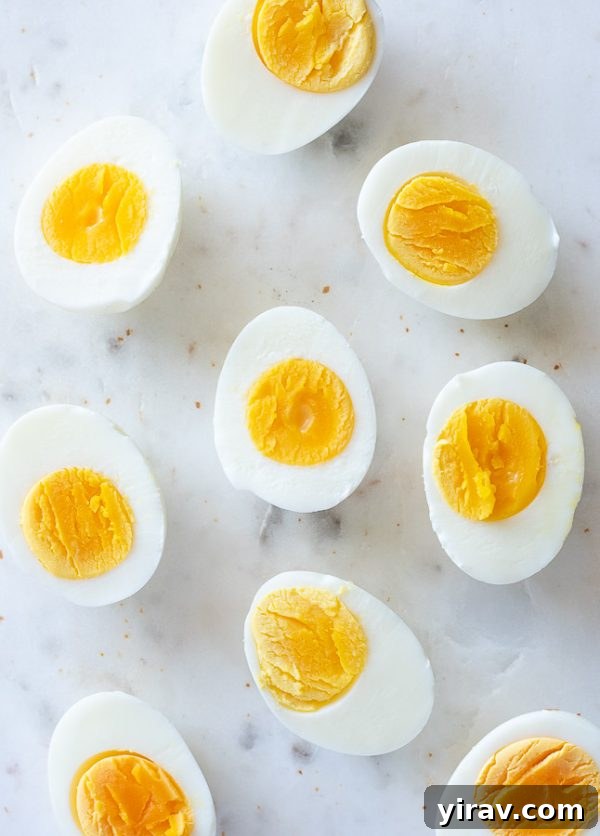 Perfectly cut hard boiled eggs with creamy yellow yolks on a marble board, ready to be enjoyed.